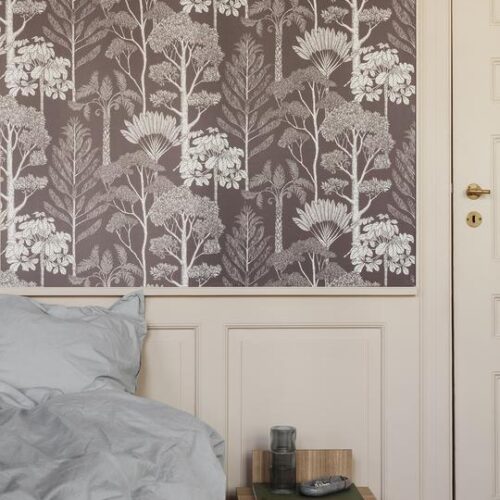 Wooden side table beside a bed with patterned wallpaper