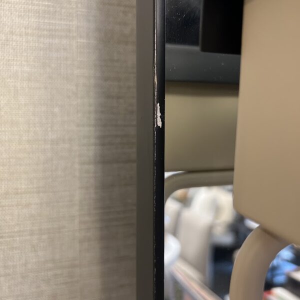 Close-up of a black-framed mirror with a small scratch on the edge