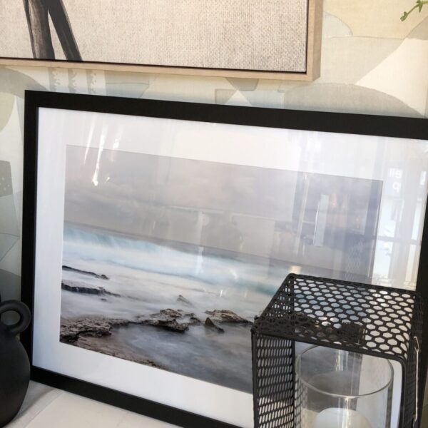 a picture of a beach and a candle on a shelf