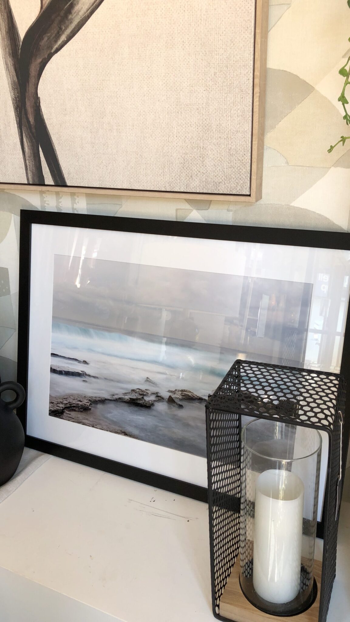 a picture of a beach and a candle on a shelf