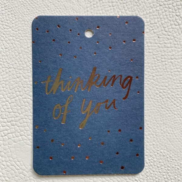 Blue card with gold foil lettering reading 'thinking of you' and small gold dots