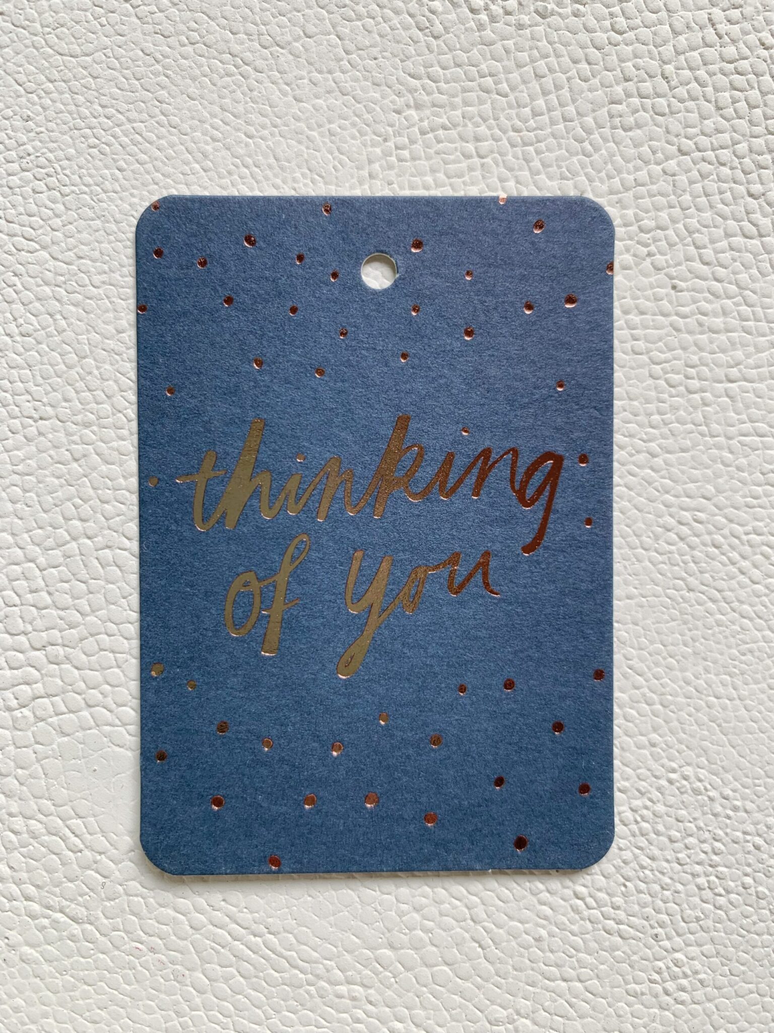 Blue card with gold foil lettering reading 'thinking of you' and small gold dots
