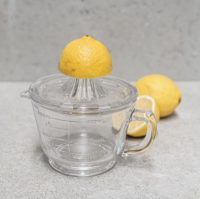 Glass citrus juicer Australia in use pressing fresh citrus into measuring jug