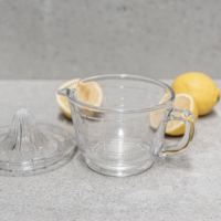 Glass citrus juicer Australia with integrated measuring jug on clean background