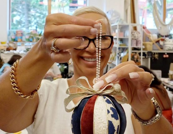 Close-up of a woman holding a decorated Christmas ornament during a workshop in a design studio.