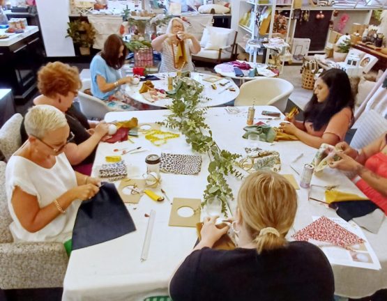 Group of women crafting Christmas decorations around a table during a workshop in a design studio.