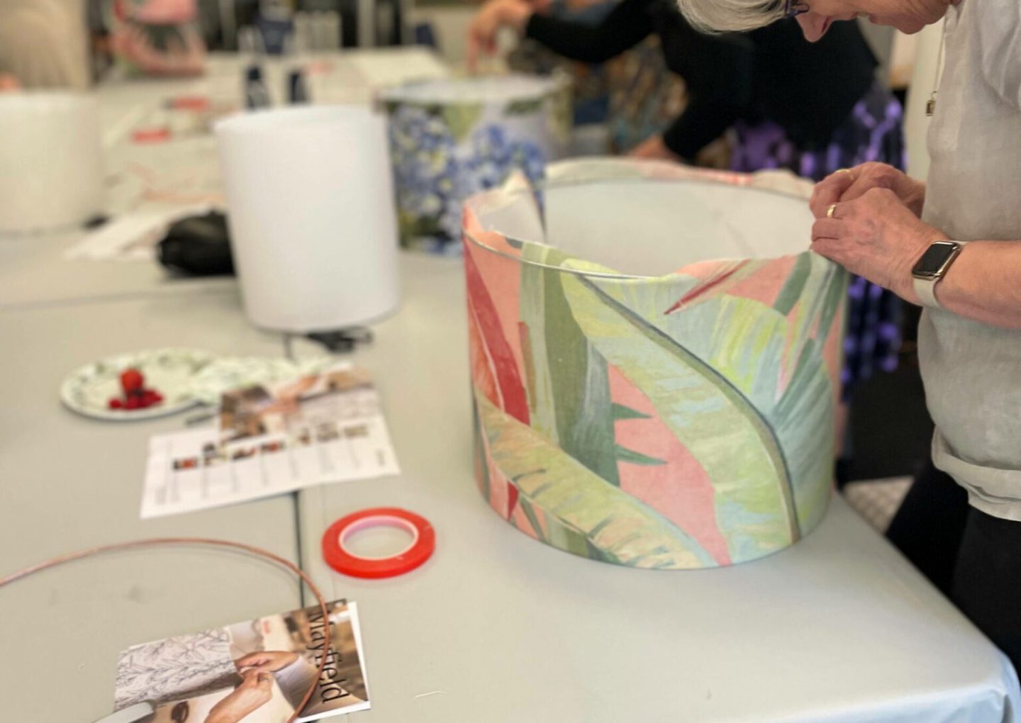 Person crafting a lampshade with colorful fabric during a workshop.