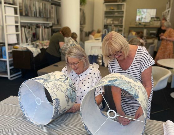 Two women working on creating fabric lampshades during a workshop in a design studio.